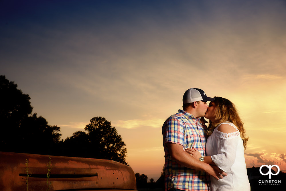 Bride and groom kissing at sunset.