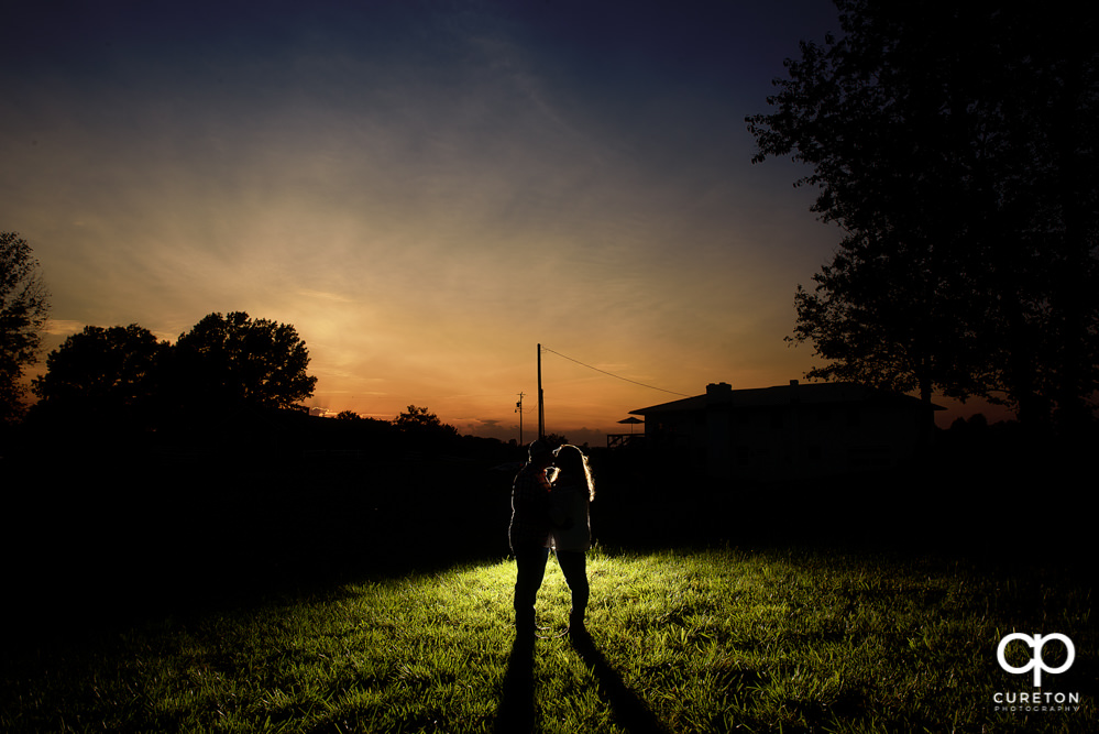 Silhouette of an engaged couple at sunset.