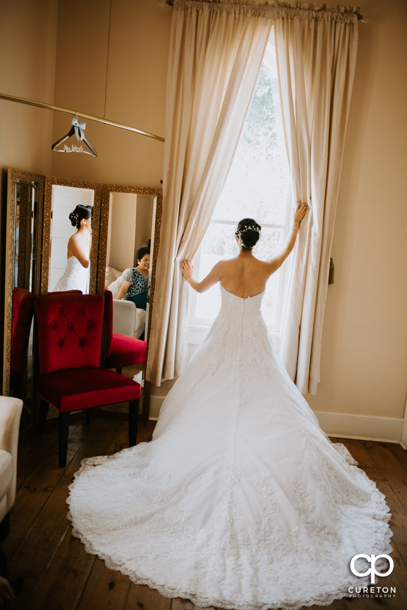 Bride looking out the window showing off the back of the dress.
