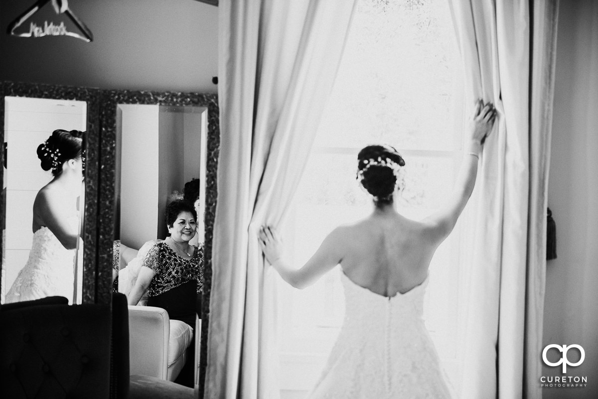 Bride's mother's reflection watching her daughter getting ready.