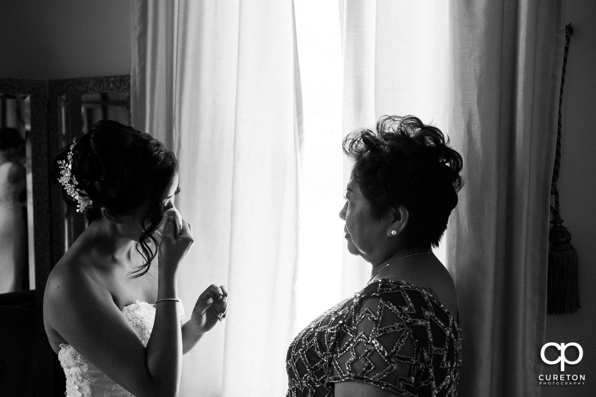 Bride tearing up as she is getting ready with her mother.