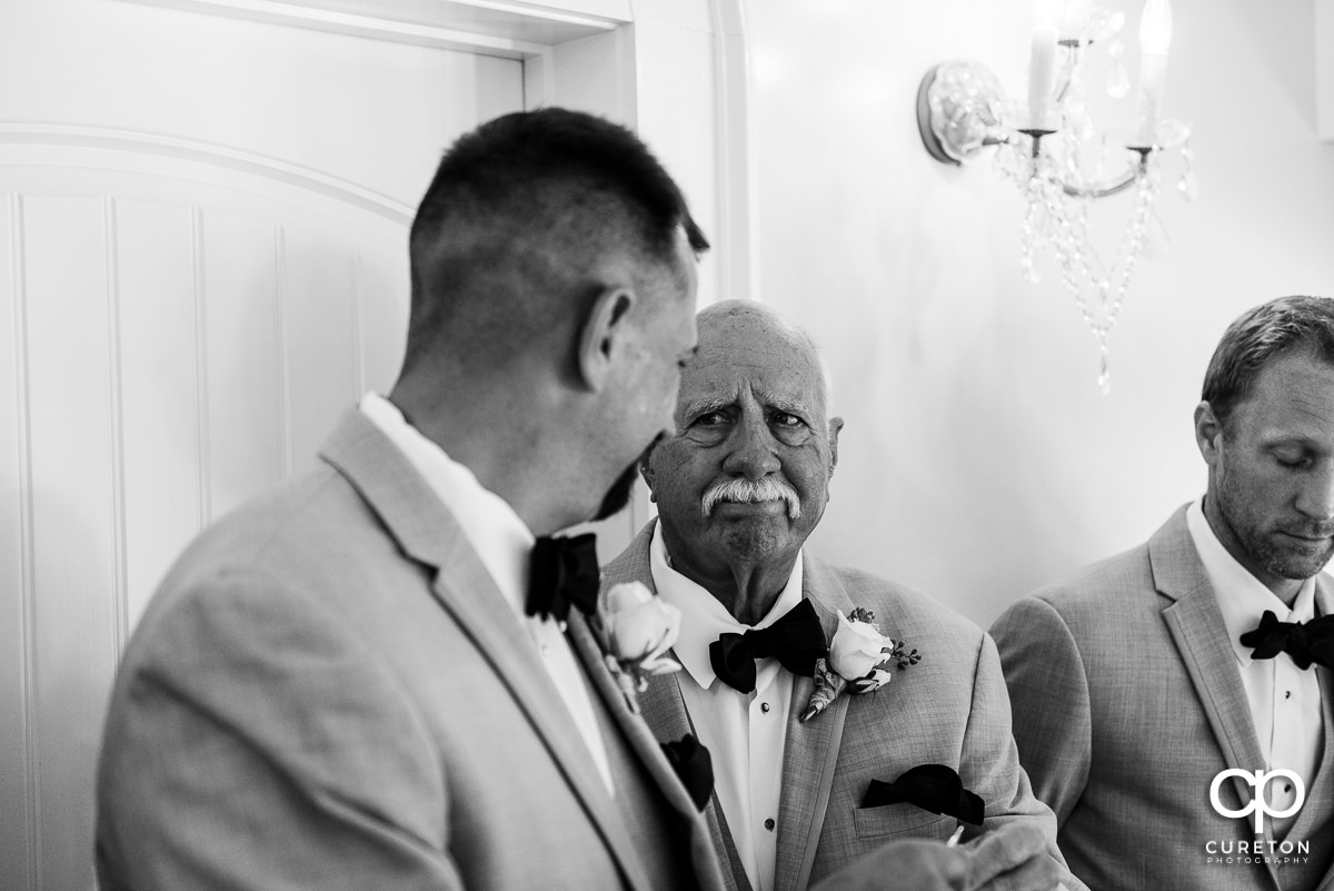 Groom's father looking on as his son is receiving a gift before the wedding ceremony.