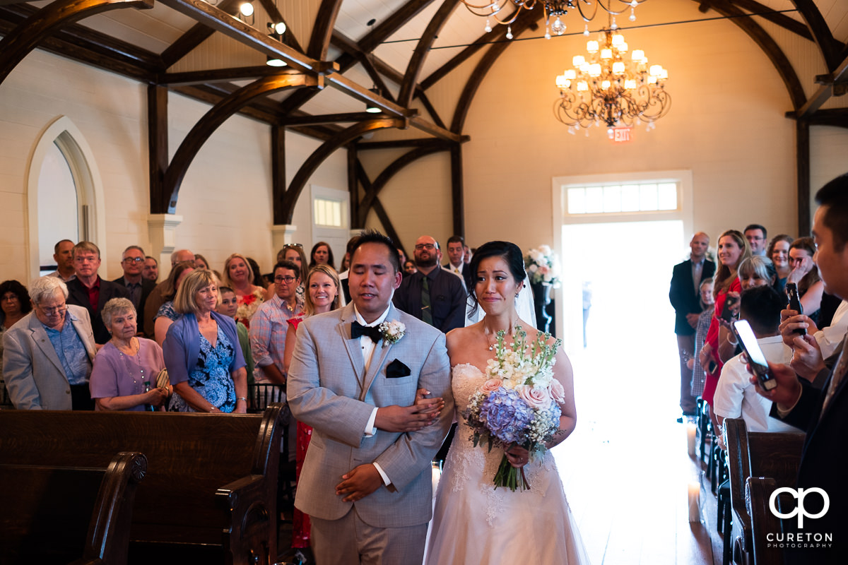 Bride and her brother walking down the aisle at the wedding ceremony at the Tybee Island Wedding Chapel.