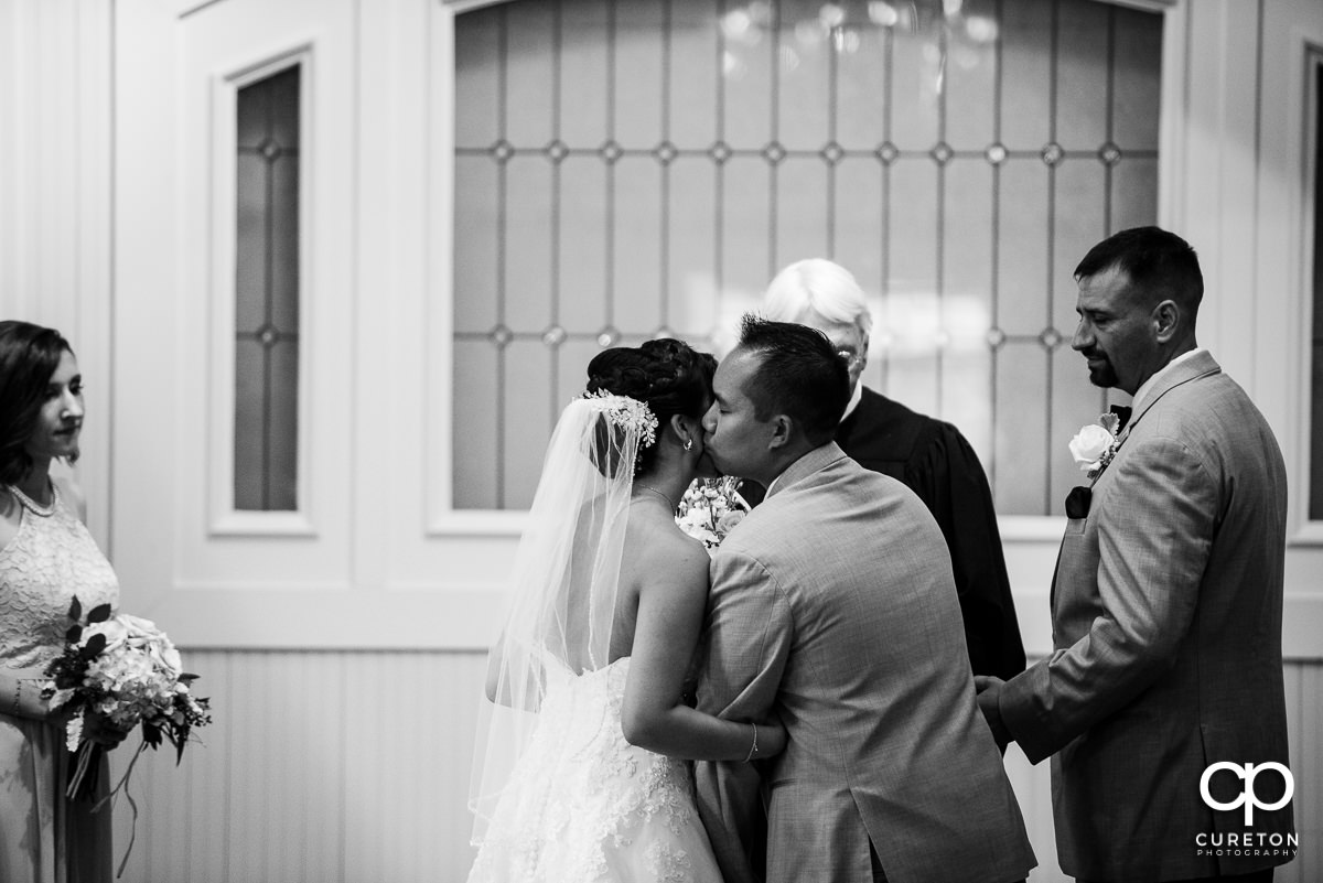 Bride's brother kissing his sister on the cheek at her wedding ceremony.