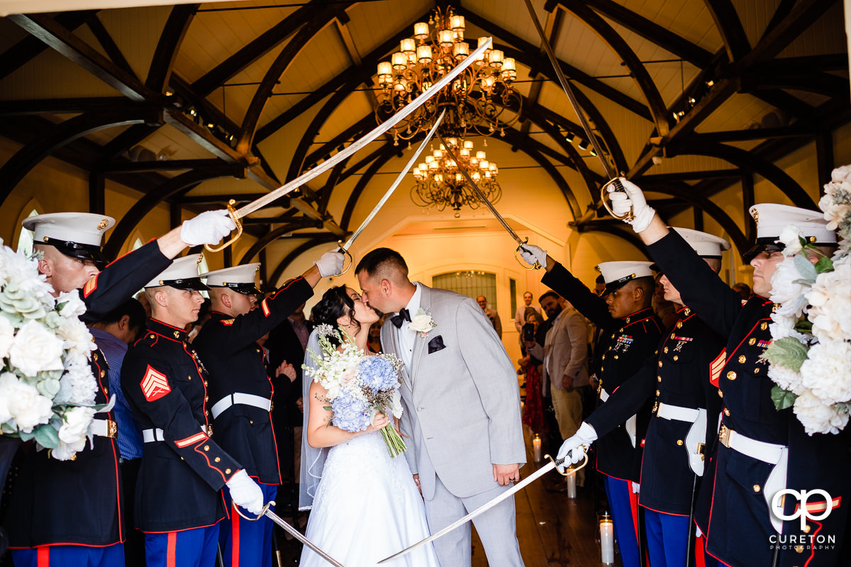 Bride and groom kissing while leaving their Tybee Island Chapel Wedding through a Marine saber arch.