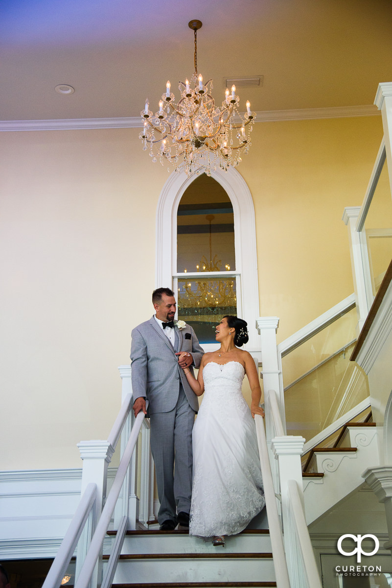Bride and groom making a grand entrance down the staircase at the Tybee Island Chapel reception.