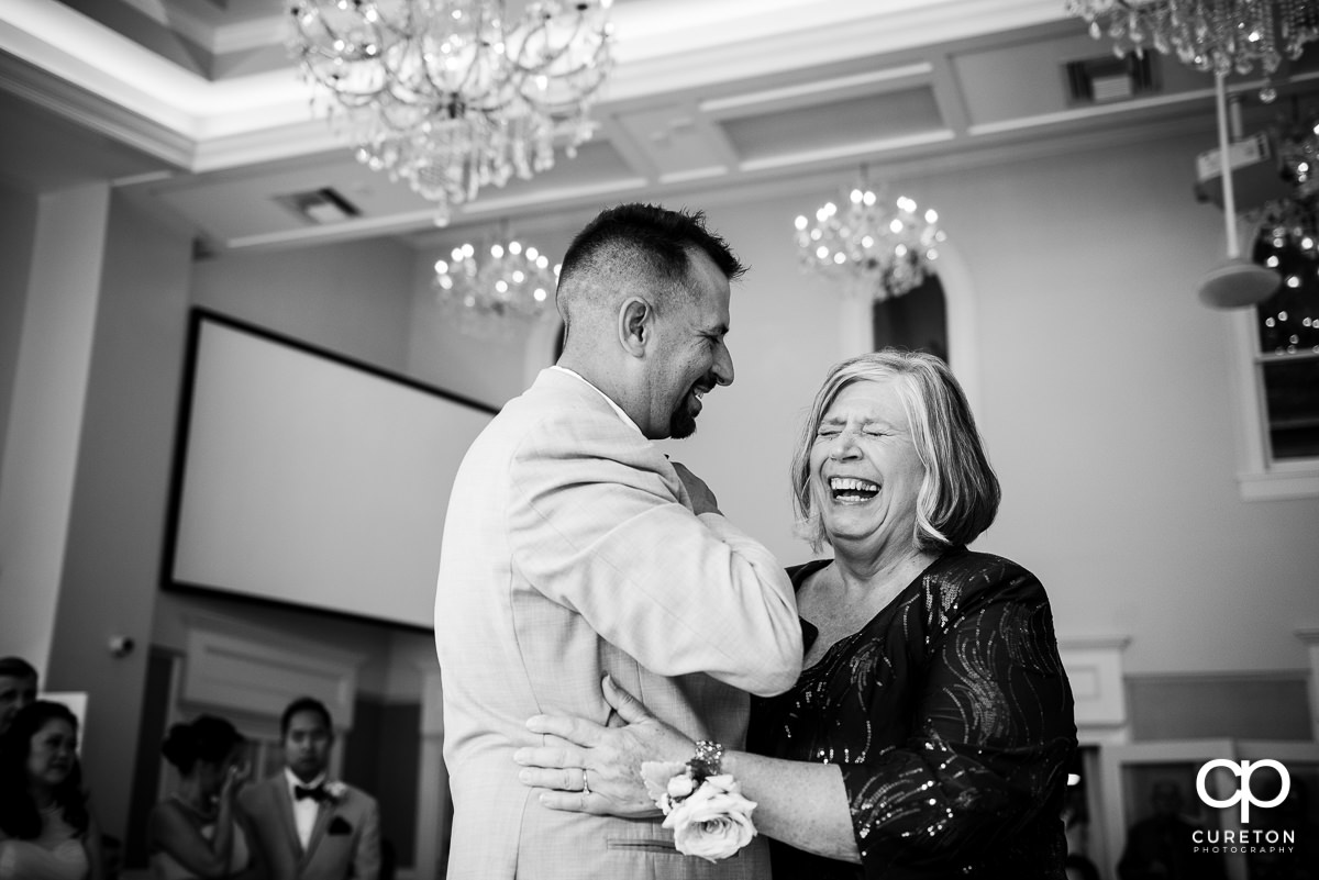 Groom's mother laughing during their dance at the reception.