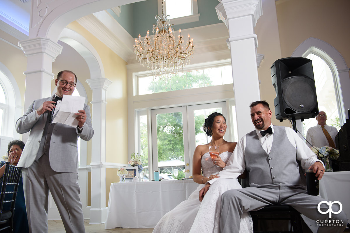 Couple laughing as the best man gives a speech.