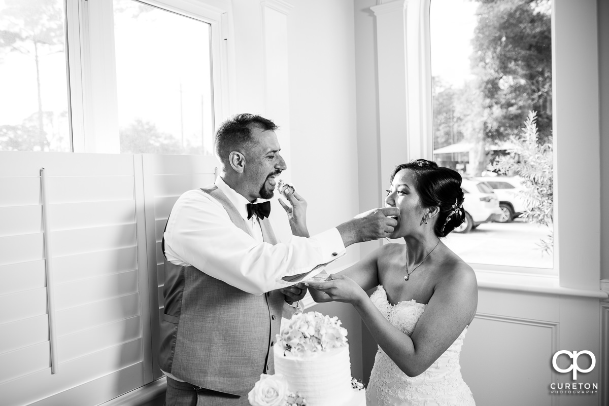 Bride and groom feeding each other cake.