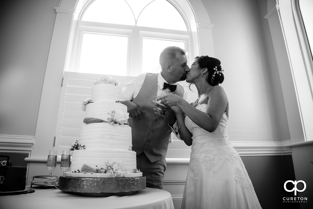 Married couple kissing at the wedding cake.