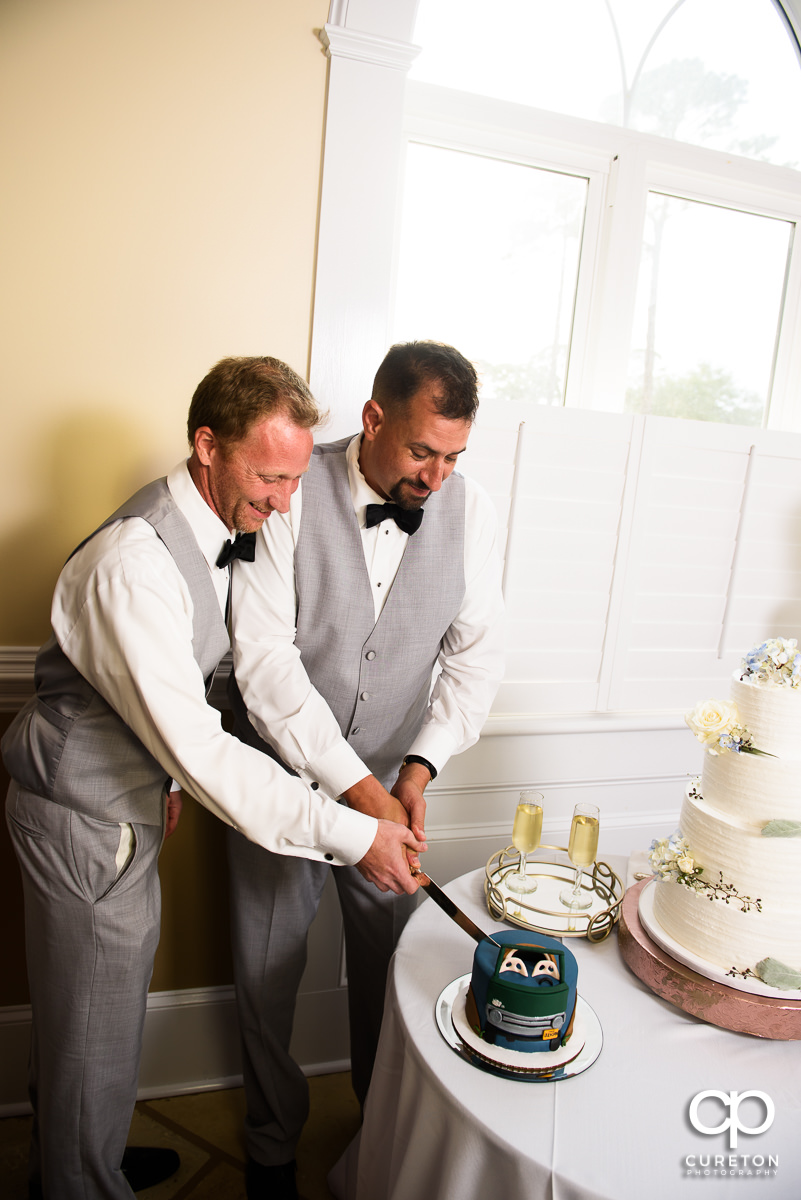 Groom and friend cutting the groom's cake.