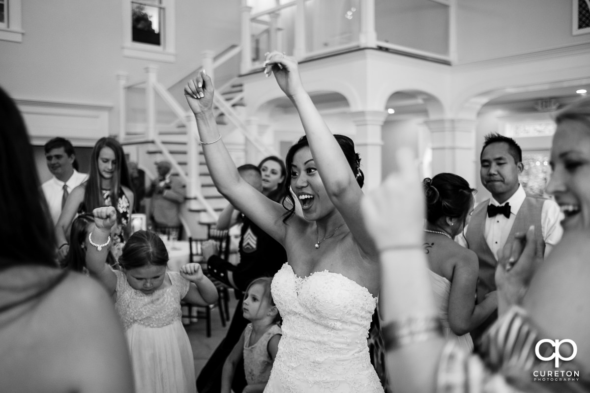 Bride dancing with hands in the air at the wedding reception.