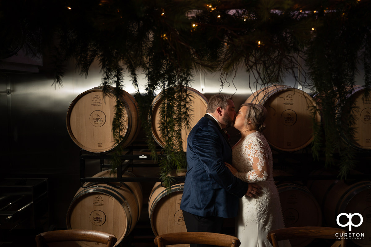 Bride and groom kissing in a winery.