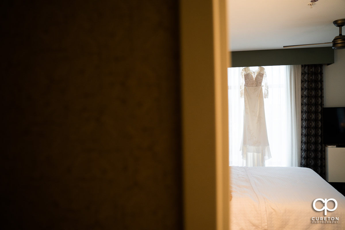 Bride's dress hanging in a hotel room.