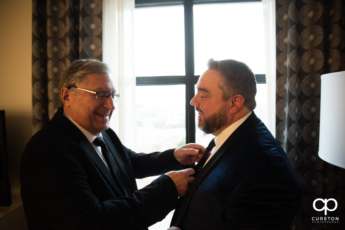Groom's dad helping him with his tie.