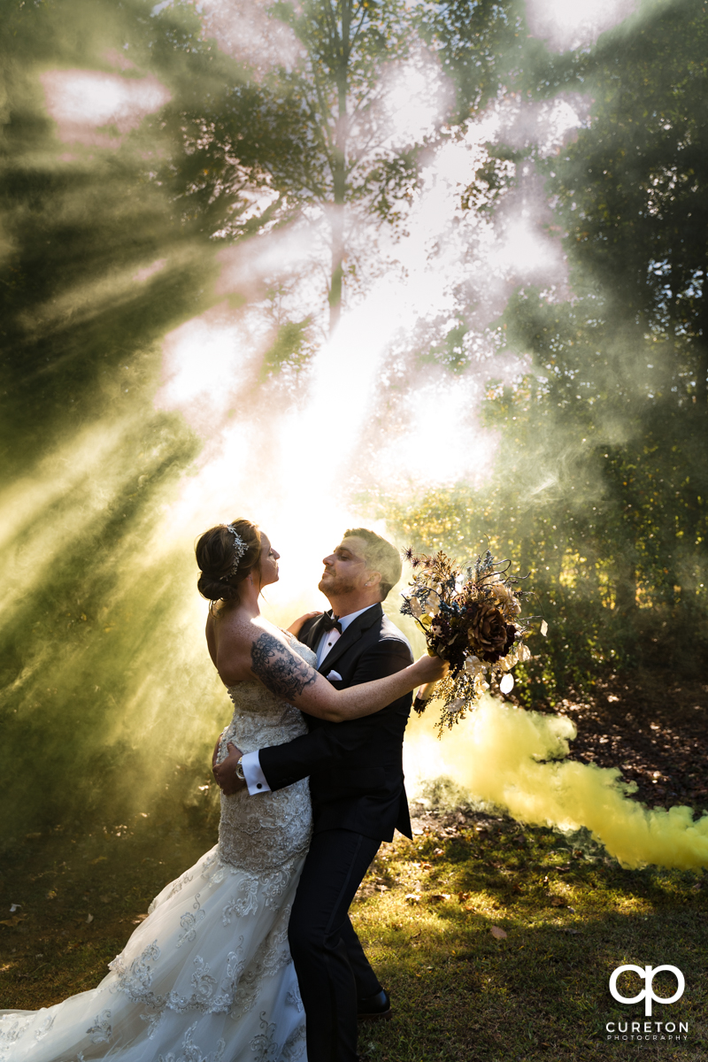 Groom lifting his bride as a yellow smoke bomb goes off at the wedding reception in Greenville,SC.