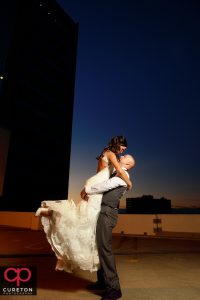Groom lifting the bride at sunset during the commerce club wedding reception.