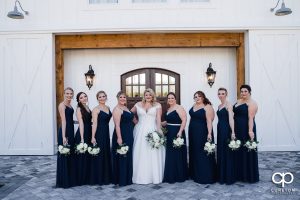 Bride and bridesmaids posing in front of a white barn.