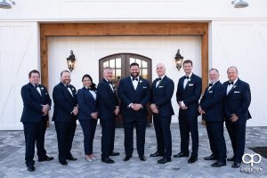 Groom and groomsmen in front of a white barn.