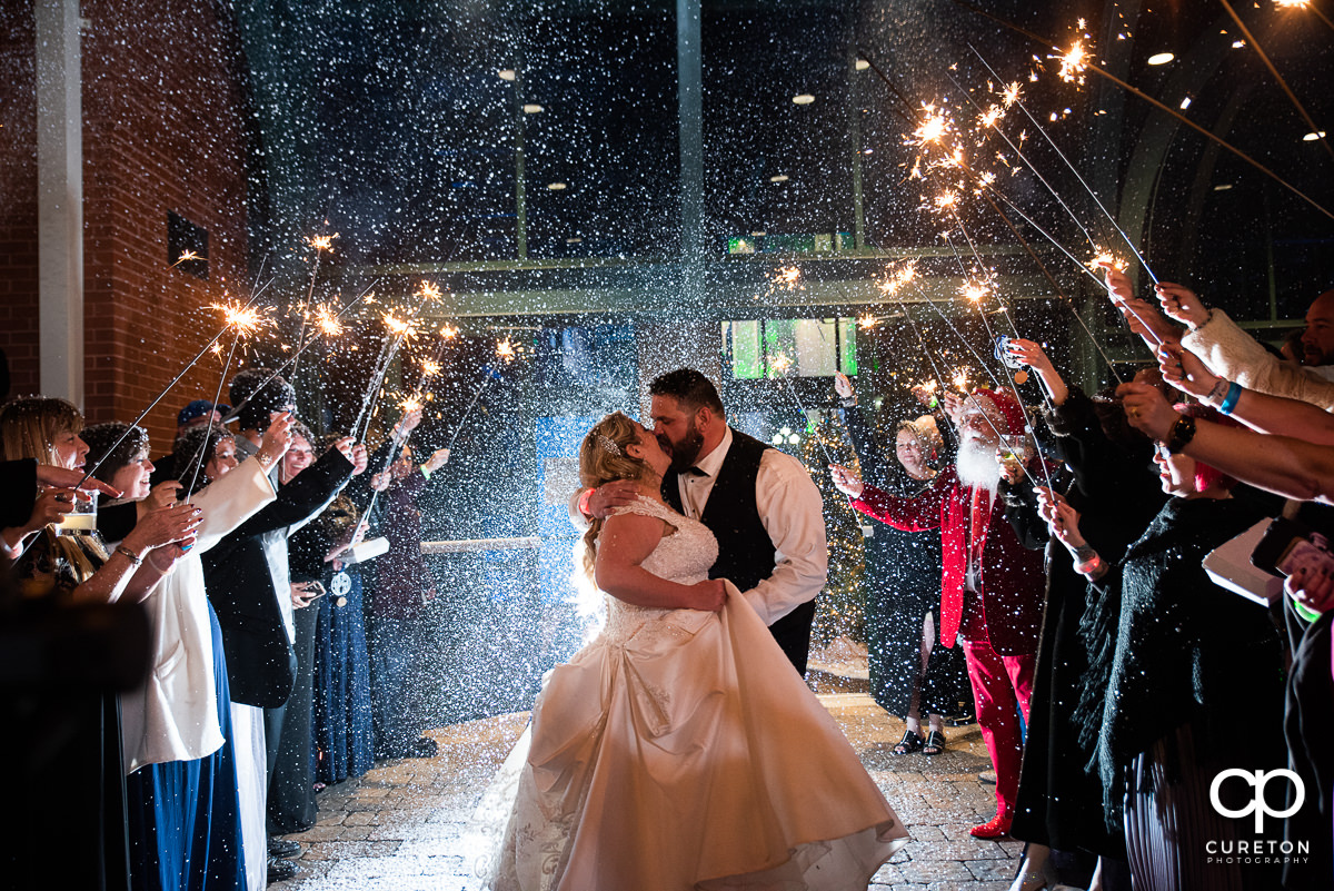 Bride and groom having a grand exit with sparklers and snow.