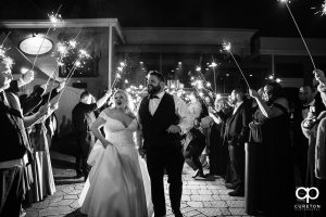 Bride and groom having a grand exit with sparklers .