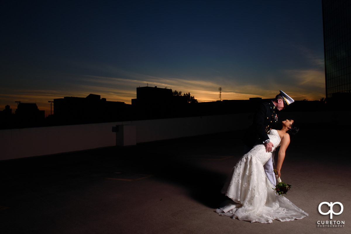 Groom dipping his bride at sunset.