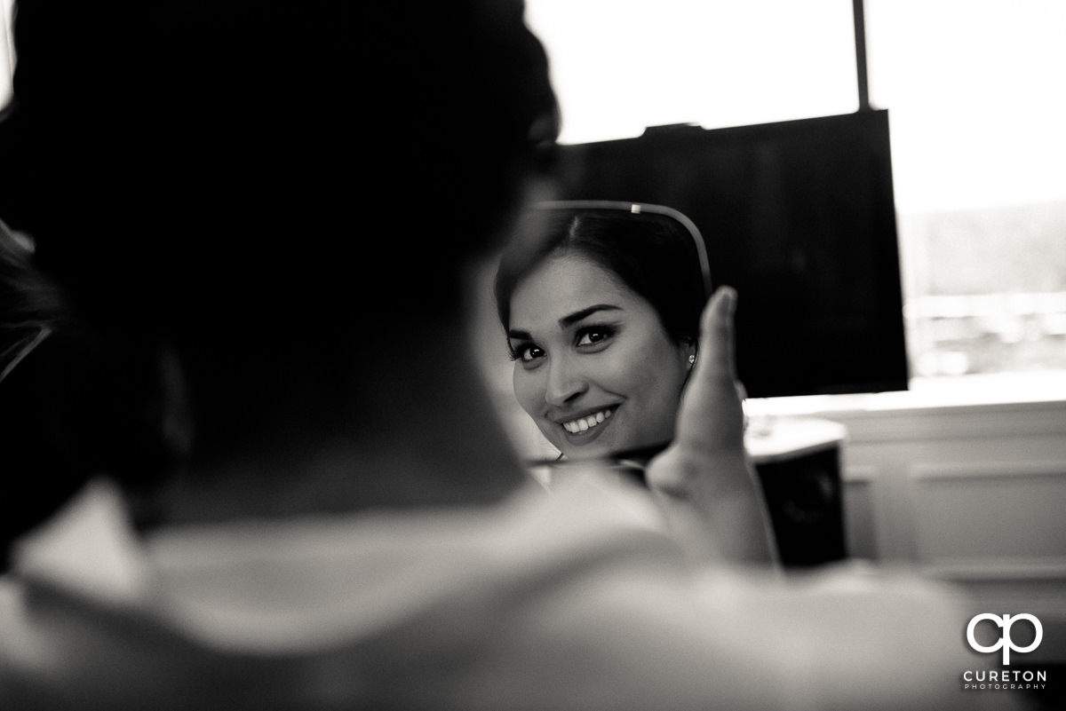 Bride seeing her makeup in a mirror before the ceremony.