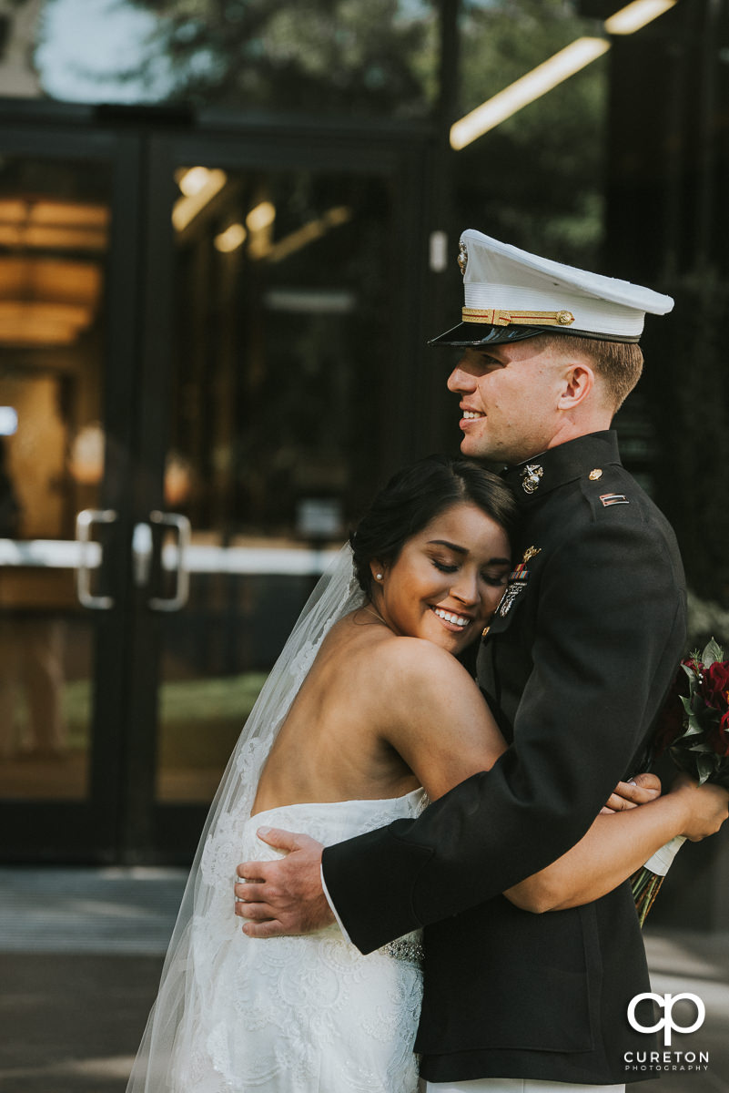 Bride hugging her groom in Marine dress uniform.