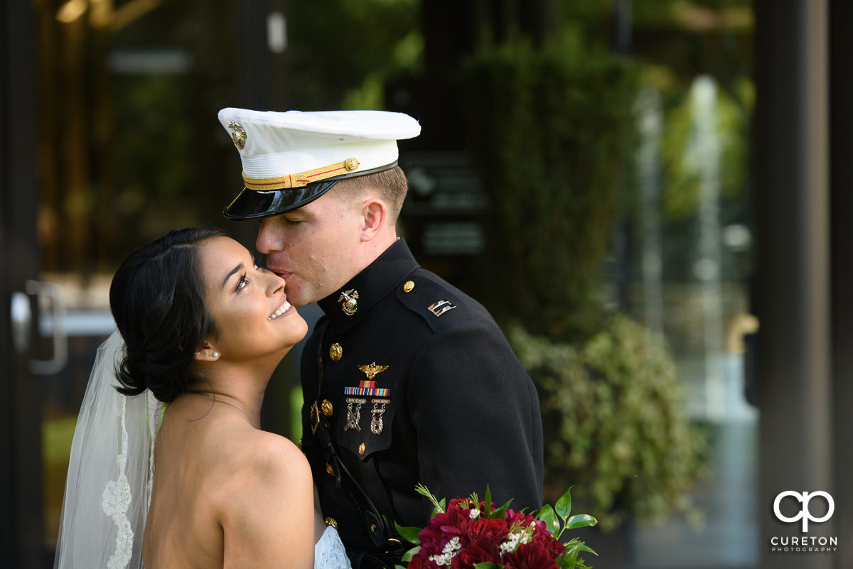 Groom kissing his bride on the cheek.