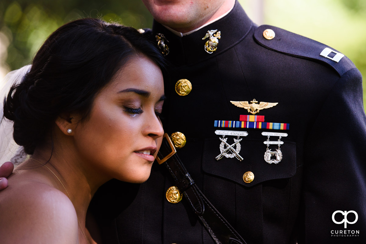 Bride crying on the chest of her groom in military uniform during a first look.