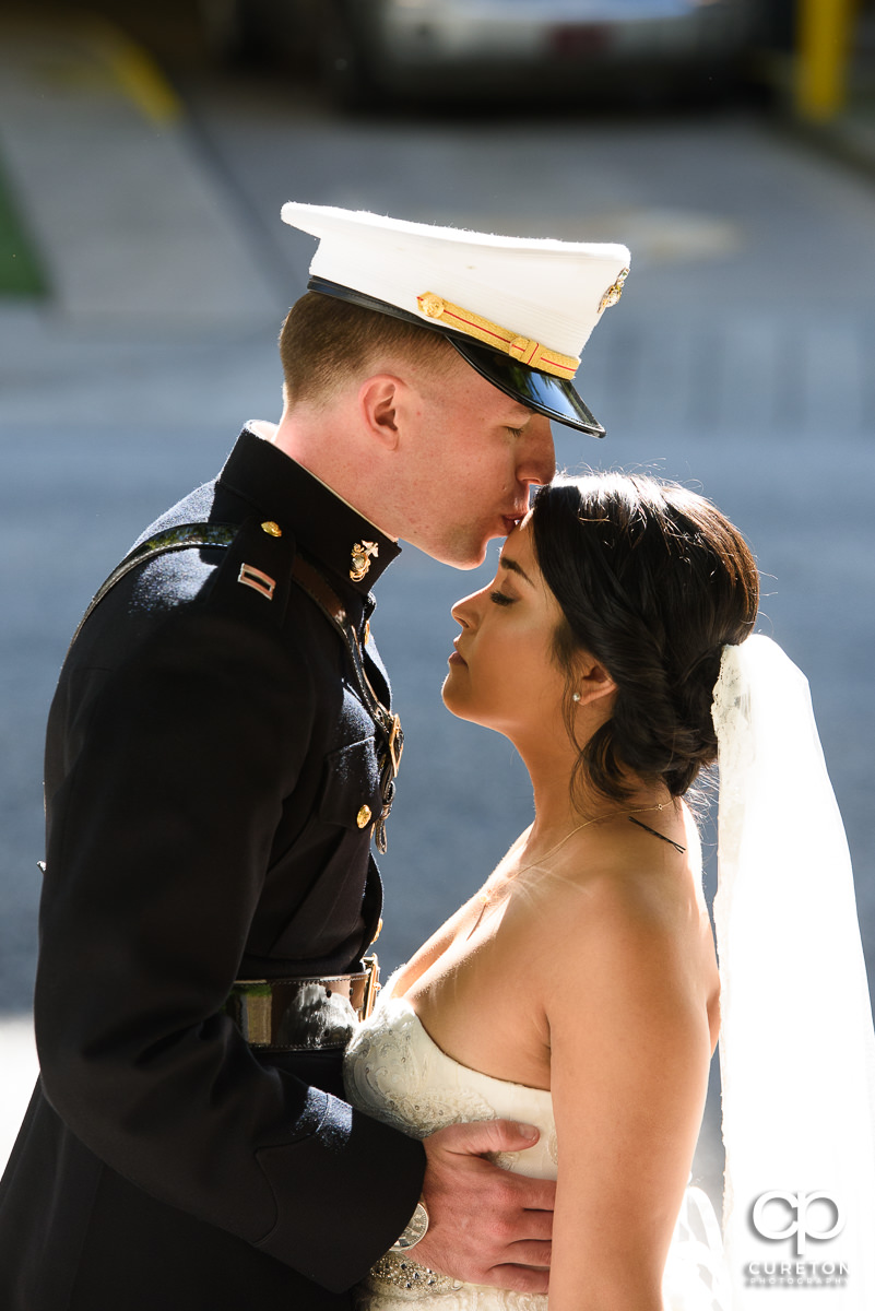 Groom kissing his bride on the forehead.