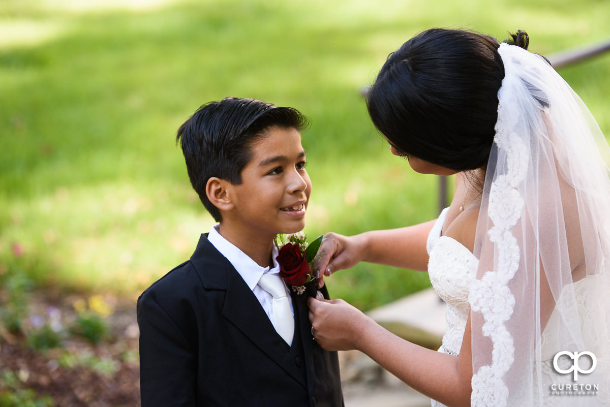 Bride putting a flower on her son.