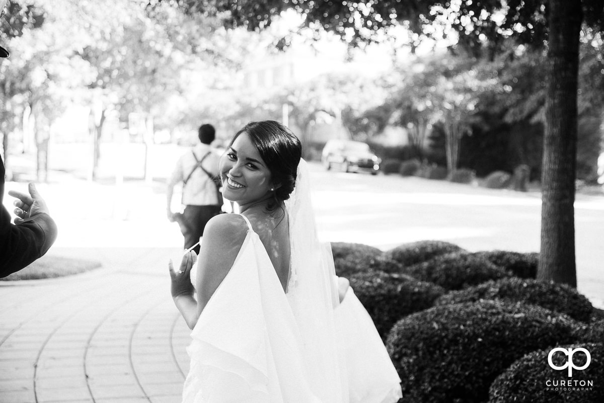 Bride looking back walking dow a sidewalk in downtown Greenville,SC.
