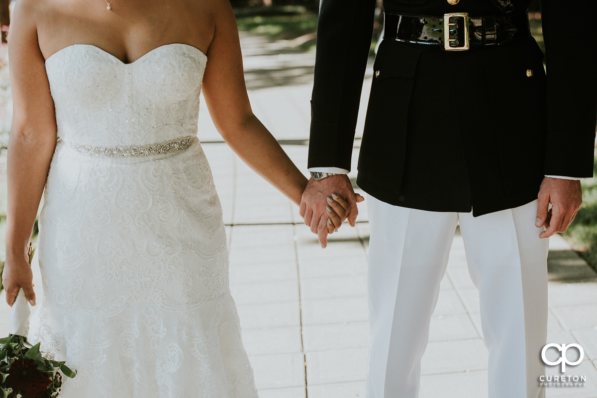 Bride and groom holding hands closeup.