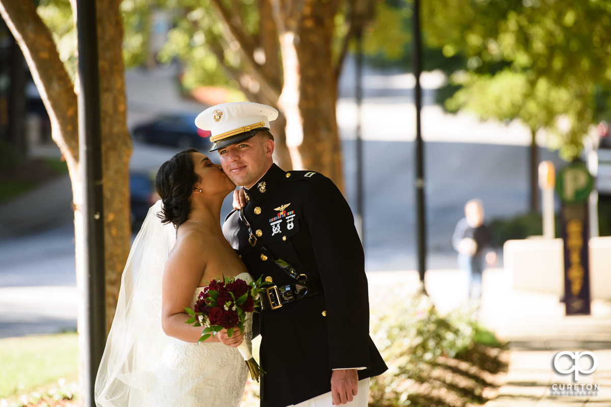 Bride kissing her groom on the cheek.