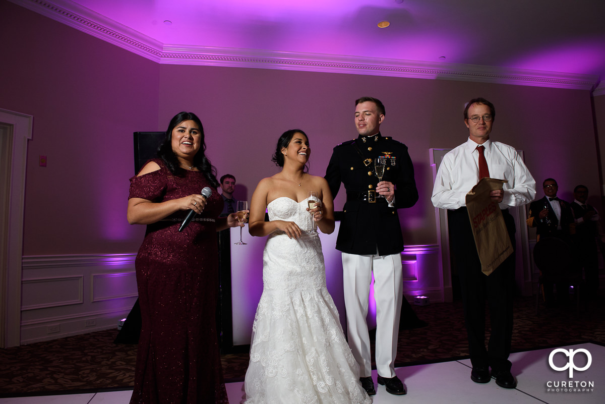 Bride and groom watching their parents give a toast.