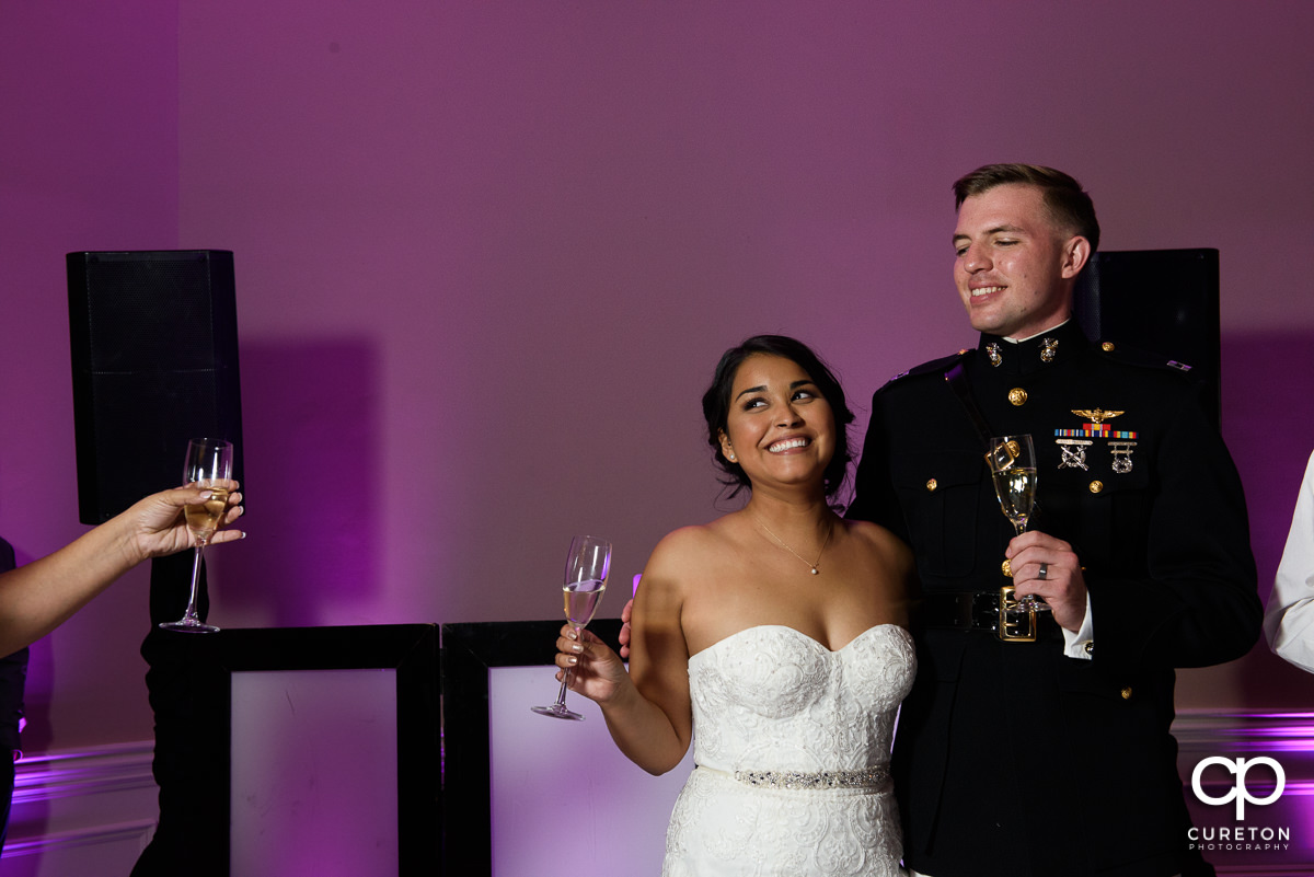 Bride smiling while her mother gives a toast.