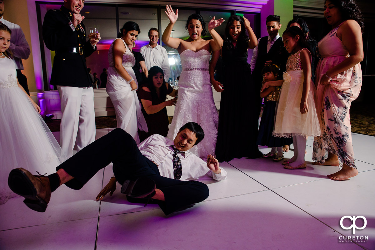 Bride cheering as a wedding guest break dances at the reception.