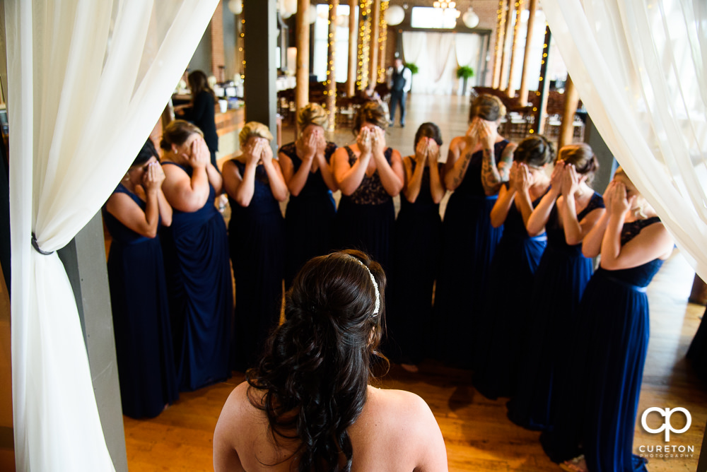 Bride ready to reveal herself in the dress to her bridesmaids.