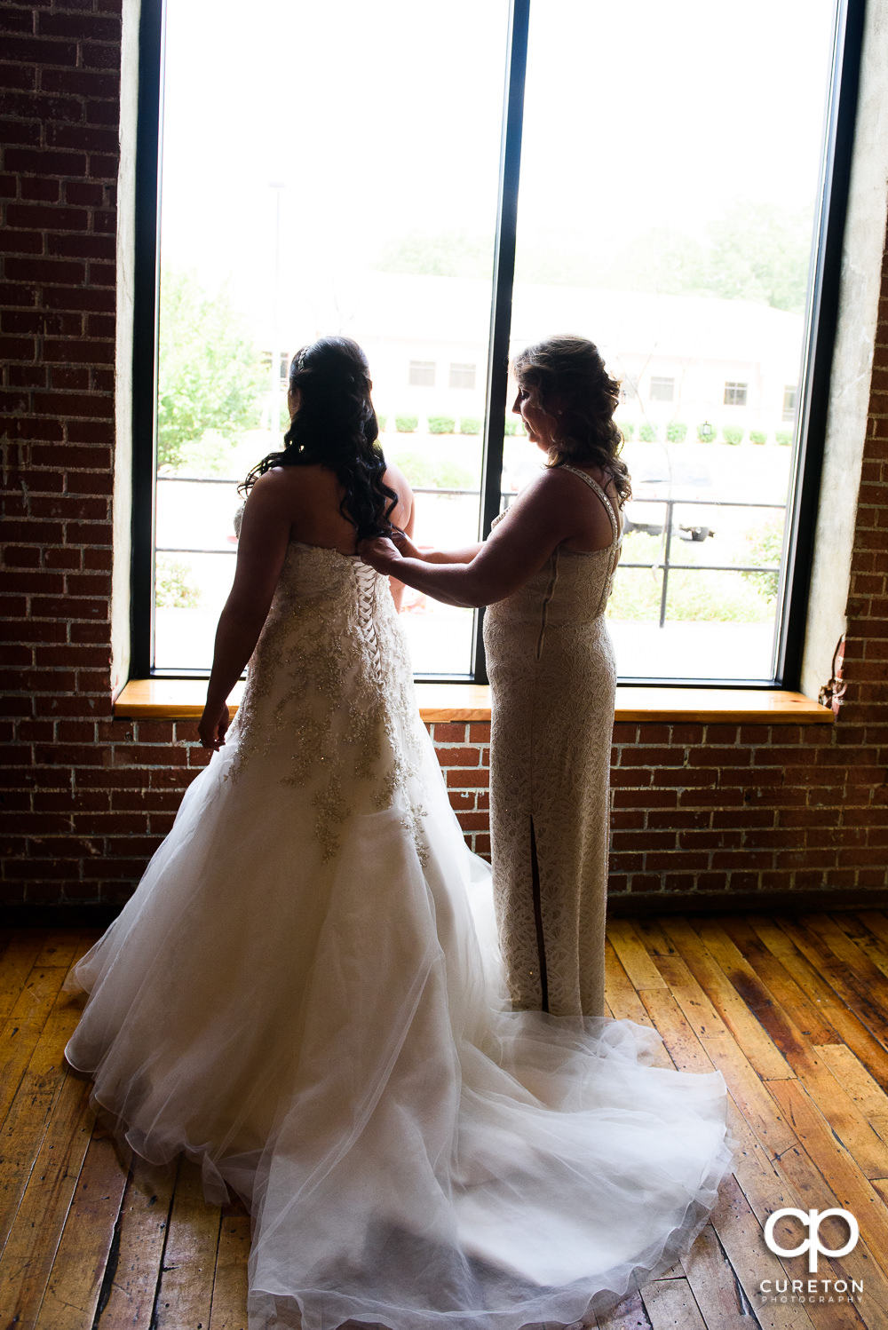Bride's mom helping her into the dress.