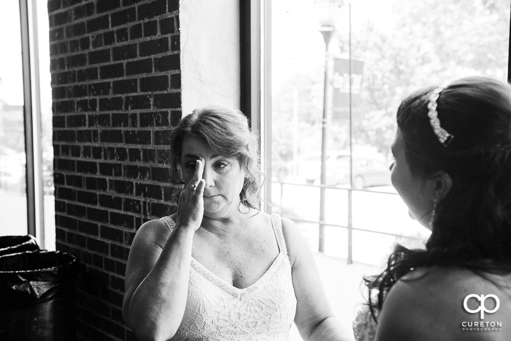 Bride's mom crying when she sees her daughter.