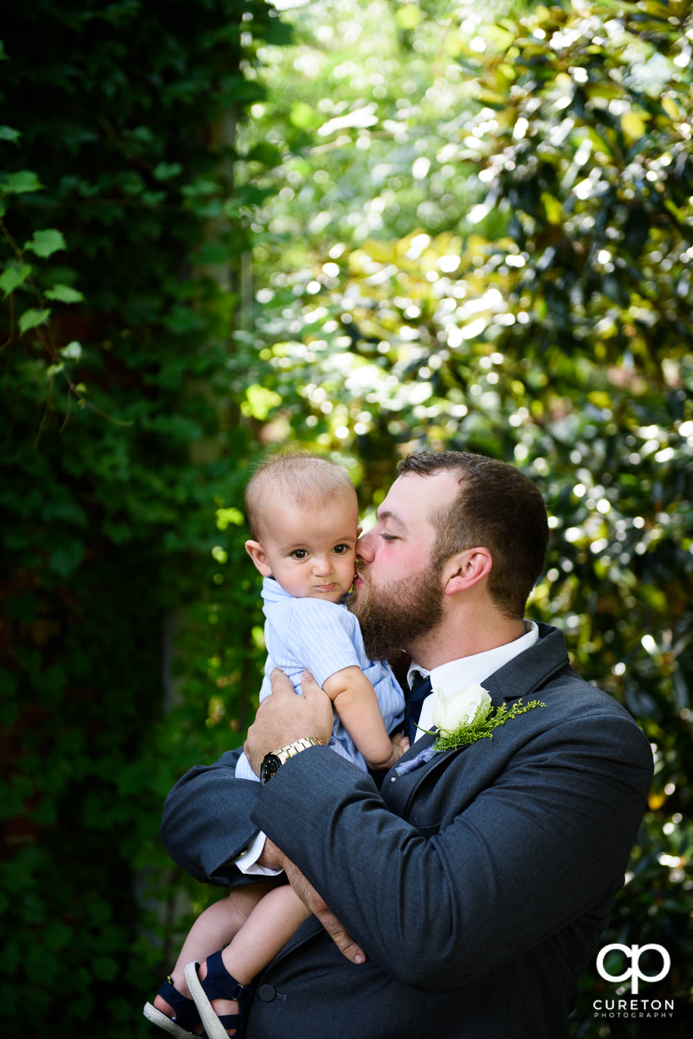 Groom kissing his infant son.