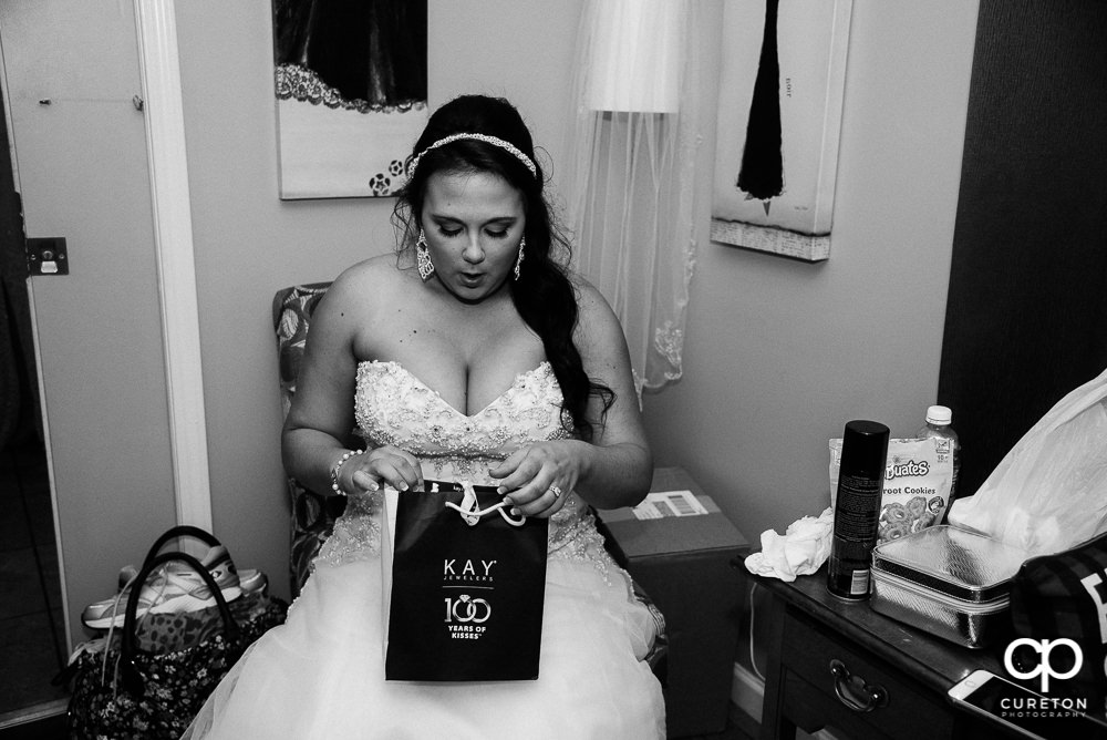Bride opening a gift from her groom.