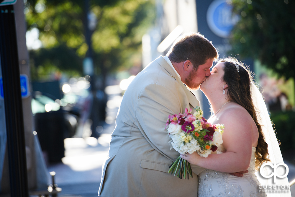 Bride kissing groom on Main St. in downtown Greenville,SC.