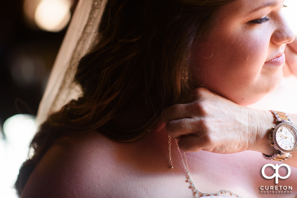 Bride putting on her jewelry.