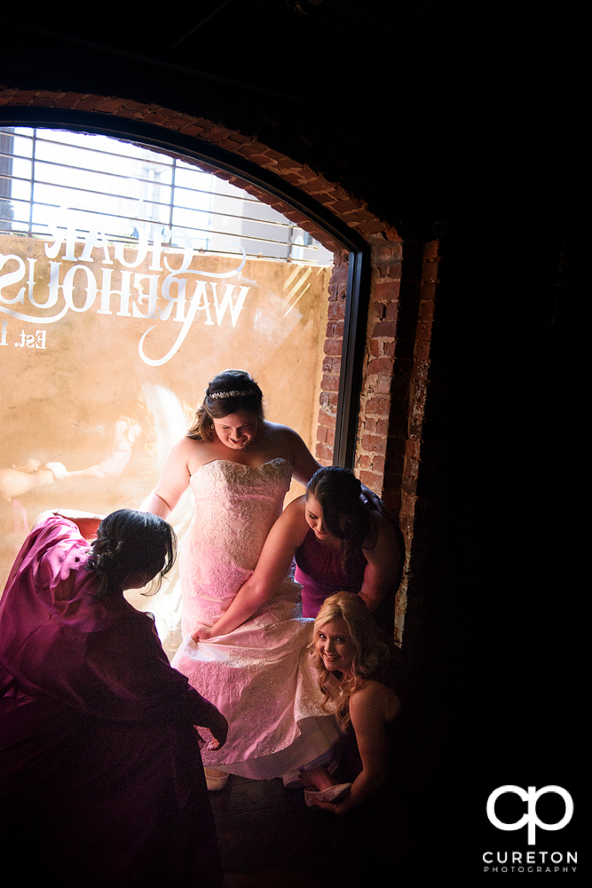 Bridesmaids helping the bride with her shoes.