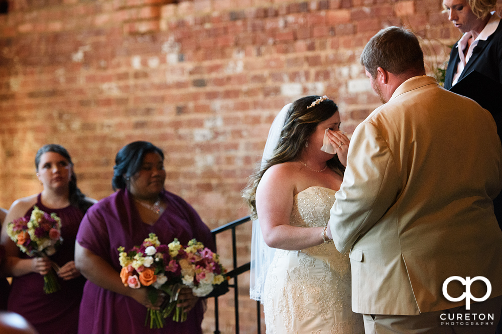 Bride wiping tears during the ceremony.