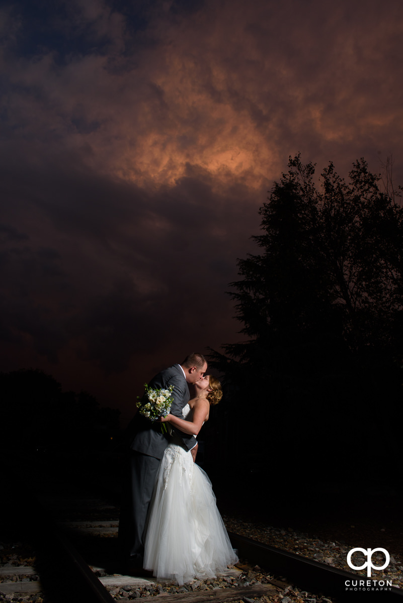 Bride and groom kissing with a purple sunset during their wedding reception at The Old Cigar Warehouse.