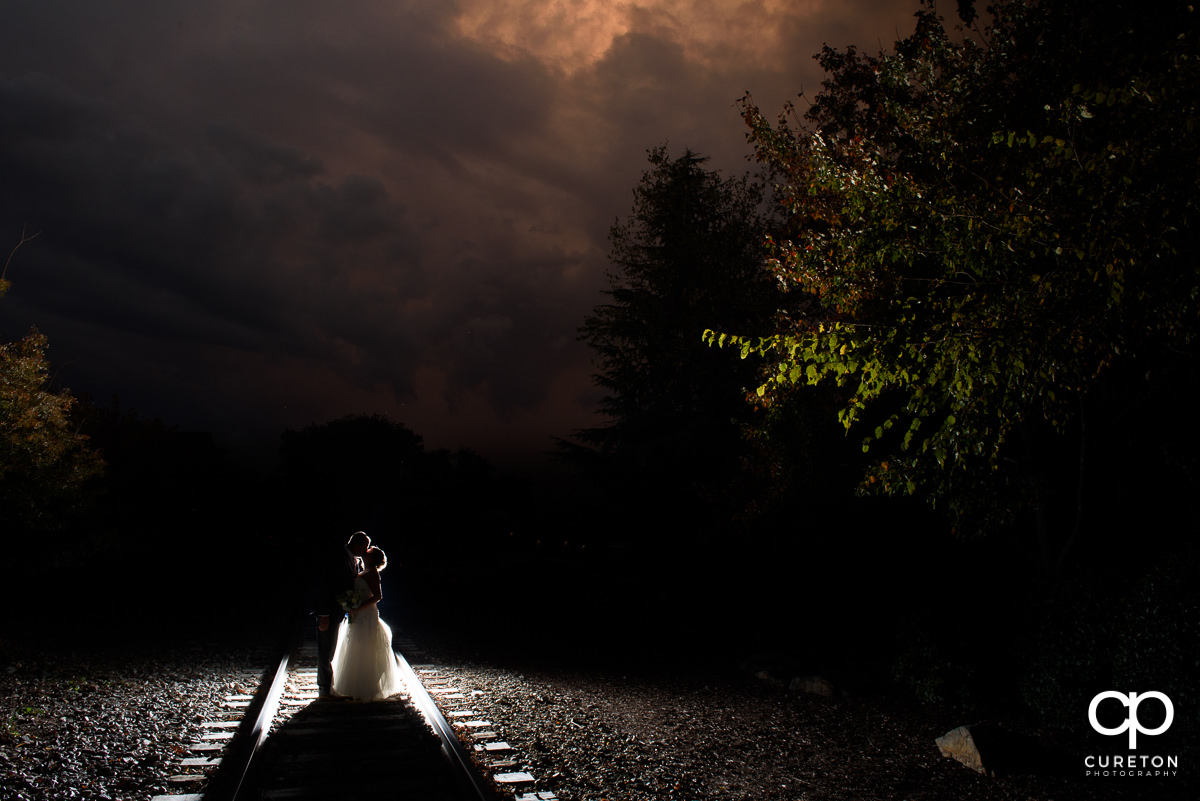 Married couple standing on the railroad tracks at sunset at The Old Cigar Warehouse.