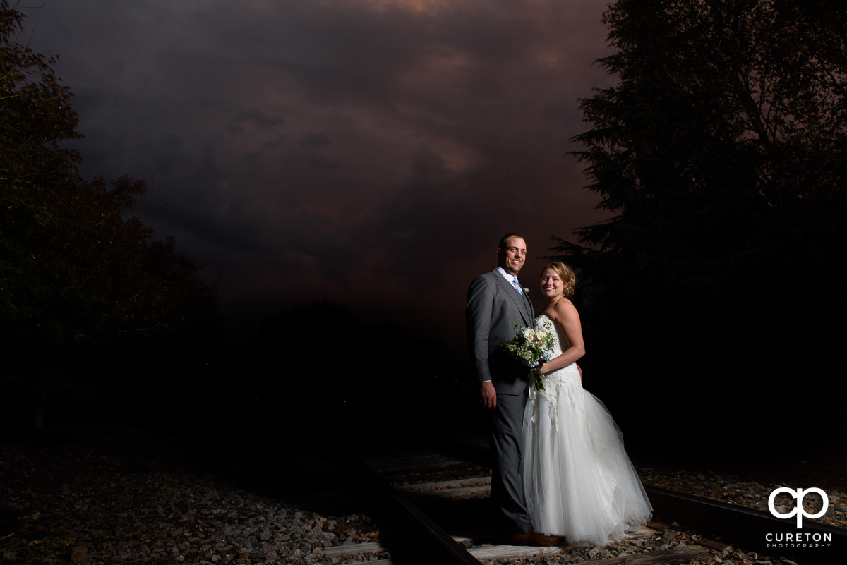 Couple standing on the railroad tracks at sunset during their Old Cigar Warehouse wedding.